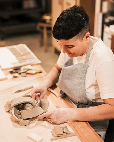 smiling-female-potter-giving-shape-mold-clay-wooden-desk.jpg